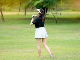 una joven golfista asiática se pone de pie para ver su trabajo durante el partido después de sacar la pelota de golf del punto de partida