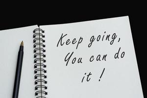 Top view of white notebook with motivational quote on dark background photo
