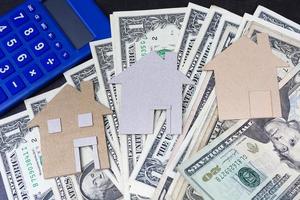 Brown paper house model with dollar banknotes and blue calculator photo