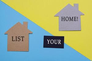 List your home text on paper house model with colored paper background photo