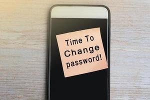 Time to change password text on notepad with smartphone on wooden desk. photo