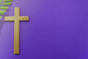 Cross and palm leaves on purple background. Lent season concept. photo