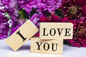 I love you text on wooden cube and with flowers bouquet background. photo