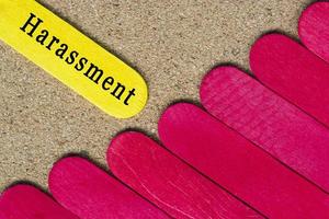 Harassment text on yellow wooden stick on wooden desk. photo