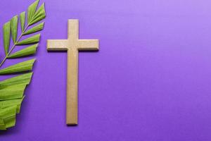 Cross and palm leaves on purple background. Lent season concept. photo