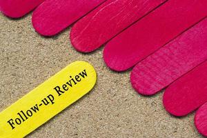 Follow-up review text on yellow color wooden stick. Business concept. photo