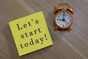 Lets start today - message with advice on yellow notepad with alarm clock photo