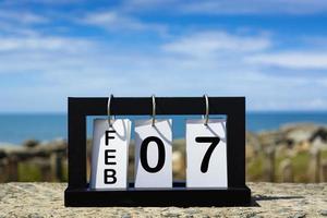 Feb 07 calendar date text on wooden frame with blurred background of ocean photo