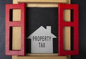 Property tax text on paper house model and in window frame on dark background photo