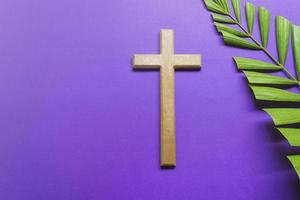 Cross and palm leaves on purple background. Lent season concept. photo