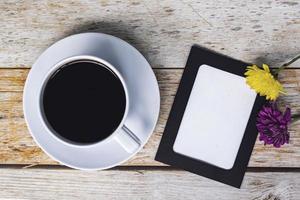 Chalkboard frame with dahlia flowers and white coffee cup on wooden desk. photo