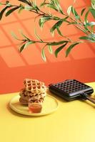 Stacked Croissant Waffle in Yellow Table and Orange Background. Croffle is Viral Cake from South Korea. photo