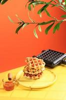 Stacked Croissant Waffle in Yellow Table and Orange Background. Croffle is Viral Cake from South Korea. Concept Pop Color Food, Copy Space for Text photo