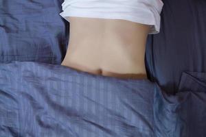 Healthy nutrition and belly health concept. Close up of woman flat stomach. Girl in bed with hungry feeling. Top view photo