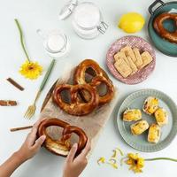 Top View Flat Lay Snacking Time with Hand, Pretzel, Biscuit, and Pastry Roll with Melted Cheese photo