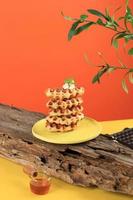 Stacked Croissant Waffle in Yellow Table and Orange Background. Croffle is Viral Cake from South Korea. Concept Pop Color Food, Copy Space for Text photo