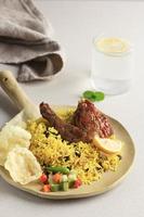 delicioso pollo biryani en plato amarillo sobre fondo blanco, comida ramzan india o paquistaní. foto