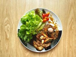 Grilled pork steak with salad on the black and white plate. Wooden table. Ketogenic or Atkins diet recipe. Low carb, high fat. Fresh vegetables. Healthy food trend. For diabetes patients. Isolated. photo