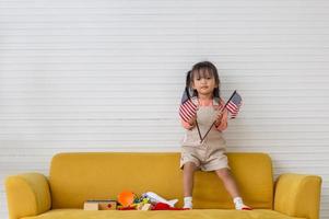 niña sosteniendo la bandera de estados unidos en la sala de estar, niña sosteniendo la bandera americana foto