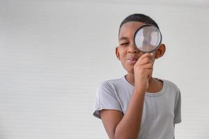 Boy holding the magnifying glass, Little kid boy holding and looking through magnifying glass showing a big eye photo