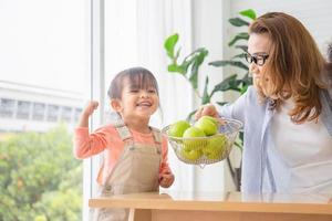 Cheerful granddaughter and grandmother enjoying with raw organic green apples, Child girl and woman with green apple fruit