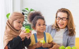 Granddaughters and grandmother enjoying with raw organic green apple, Children and woman biting green apples with smile photo