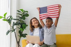 niño pequeño sosteniendo la bandera de estados unidos en la sala de estar, niño pasando tiempo feliz con la abuela