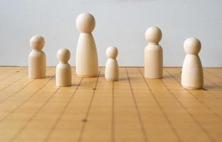 figura de madera de varios tamaños colocada en un tablero de ajedrez que representa la diversidad de personas y familias foto