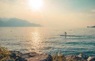 hombre en una tabla de surf con remo en el lago leman, suiza foto