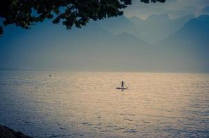 Man on a surfboard with paddle on Lake Leman, Switzerland photo