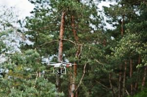 Drone quad copter with high resolution digital camera against pine forest. photo