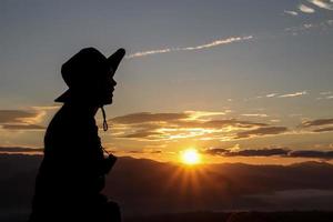 silhouette Young woman traveler looking at sunrise over the mountain. photo