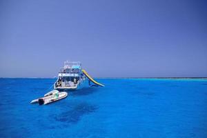 ship and boats in the blue sea water on reef photo