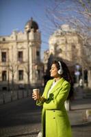 Young woman listening music with headphones on the street photo