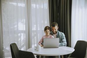 Father and daughter using laptop computer together photo