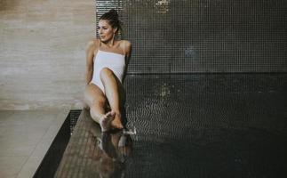 mujer joven relajándose junto a la piscina de la piscina cubierta foto