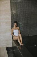 Young woman relaxing on the poolside of indoor swimming pool photo