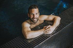 retrato de un joven sonriente que se relaja al borde de la piscina foto