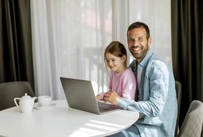 padre e hija usando una computadora portátil juntos foto