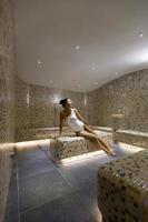 Young woman relaxing on the tepidarium bed in the spa photo