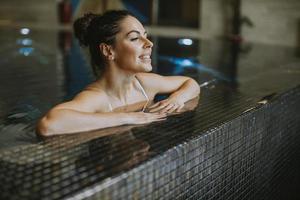 mujer joven relajándose junto a la piscina de la piscina cubierta foto