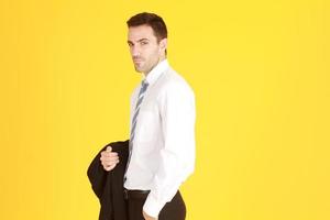 Handsome and smart businessman in suit and white shirt relaxing on isolatred on yellow background. photo