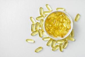 Top view of Gold fish oil in bowl isolated on white background view. Flat lay of Supplementary food. Omega 3. Vitamin E. Capsules salmon fish oil. Copy sapce. photo