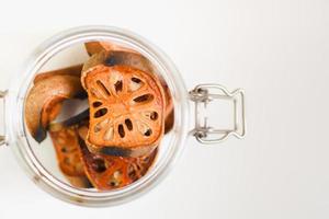 close-up top view of dried bael fruit, sliced into thin slices in a glass jar. photo