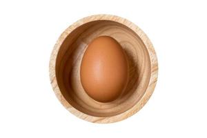 Close up of organic raw egg in wooden bowl isolated on white background.Clipping path included. photo