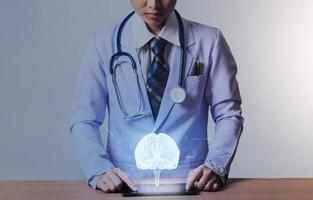 concepto médico y tecnológico futurista, doctora con dispositivo inteligente y modelo cerebral para la anatomía del cerebro foto