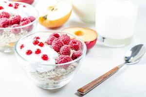 Oatmeal porridge with raspberries and red currant in bowl on white table photo