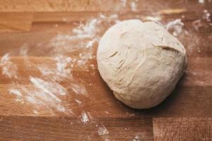 Homemade dough on floured wooden board photo