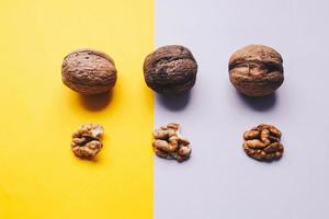 Top view of three whole walnuts on yellow and purple background. Concept food photography photo