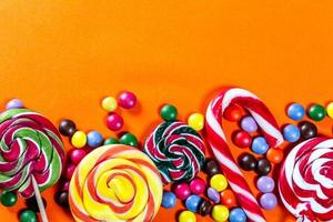 Colorful lollipops and candies on orange background photo